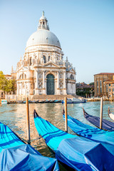 Fototapeta na wymiar Venice cityscape view on Santa Maria della Salute basilica with gondolas on the Grand canal in Venice