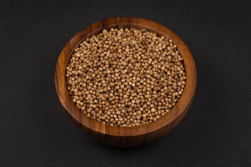 Coriander seeds in  small wooden bowl