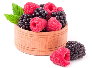blackberries and raspberries spilled from wooden bowl isolated on white background