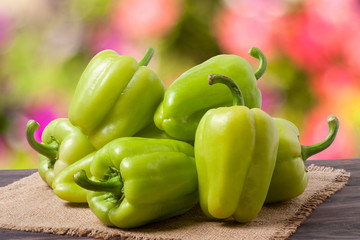 pile green pepper on a wooden table with blurred background