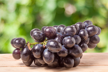 bunch of blue grapes on a wooden table with  blurred background