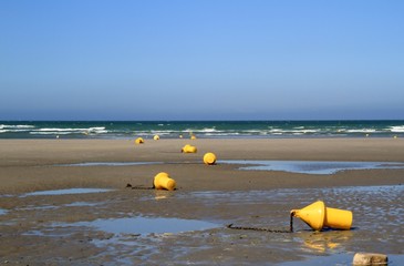 Gelbe Bojen am Strand bei Ebbe