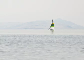 Zelfklevend Fotobehang A peaceful boat sailing on the Great Salt Lake with mountains in the background. © Andriy Blokhin