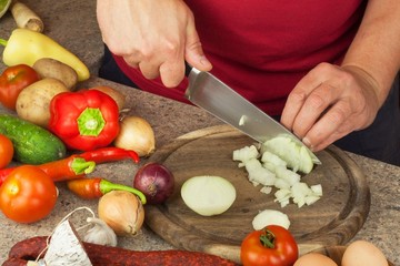 Chef sliced onion on board. Preparing vegetables for healthy salad. Slicing onions and tomatoes. Fresh vegetables in the kitchen.
