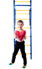 Little boy standing next to colorful stairs and holding a red heart on a white background