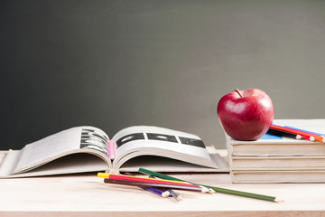 School books and apple against blackboard