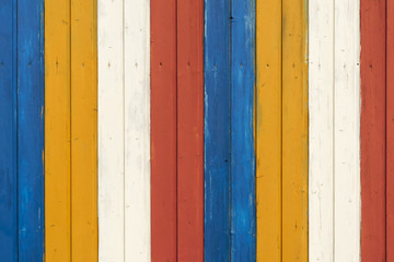 Bunte Holzwand / Hintergrund aus einer bunten Holzwand gestreift weiss, gelb, blau, rot.