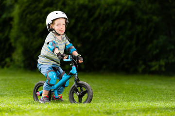 Child on balance bike with protective gear