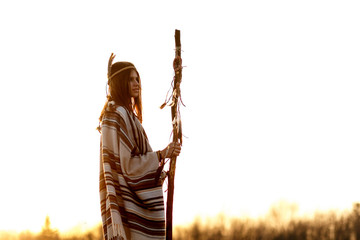 boho woman  shaman with pikestaff on background in sunset light