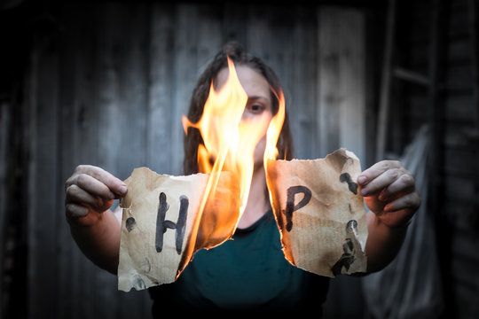 A girl holding a sheet of paper with the word "help". In the center of the sheet is a fire.
