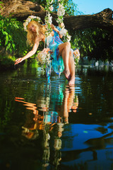 Fototapeta premium Girl on swing over river
