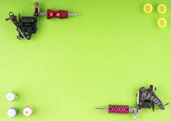 Tattoo machines with three bottles of ink and three ink containers on green background