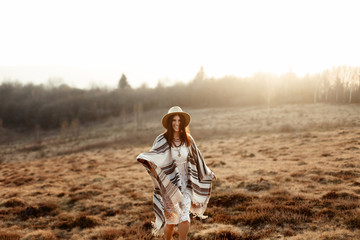 beautiful boho woman hipster, smiling and standing at sunset in