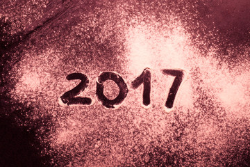 Figures 2017 on flour spilling on black metal background. Toned