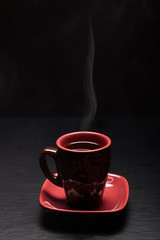 Cup of coffee with smoke on black background