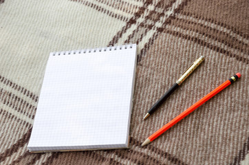 notebook with pencil and notes on coverlet in flat lay.