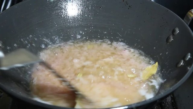 Stirring onions paste with the bay leaf and green cardamoms