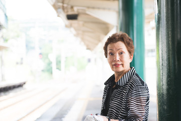 駅のホームに立つシニア女性