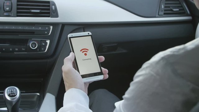 man sitting in a car and hold a smart phone that connects to wifi