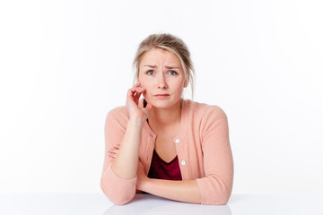 unhappy young blond woman sitting, expressing innocence and fear