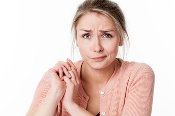 innocent young blond woman with her hands together being sorry