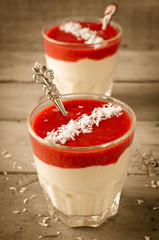 Creamy dessert with strawberry sauce and coconut flakes in glasses