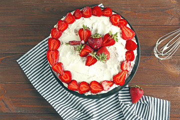 Appetizing cake decorated with strawberry on wooden table
