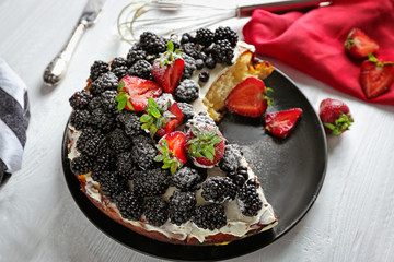 Delicious sliced cake decorated with berries on the table