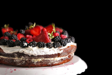 Delicious cake decorated with berries on black background
