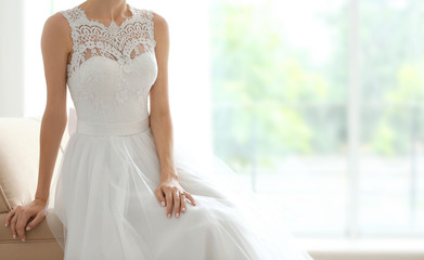 Fototapeta premium Bride in beautiful wedding gown sitting on sofa