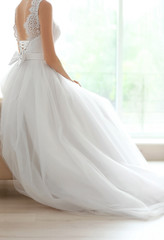 Fototapeta na wymiar Bride in beautiful wedding gown sitting on sofa