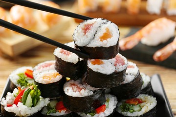 Tasty sushi roll with black chopsticks, closeup