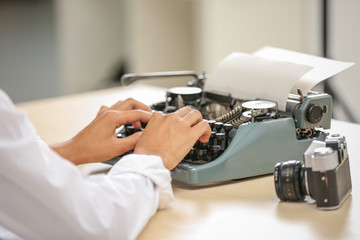 Fototapeta na wymiar Man working on retro typewriter at desk