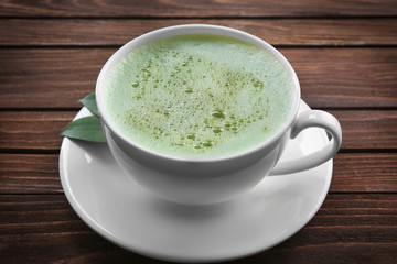 Cup of fresh matcha tea on wooden background