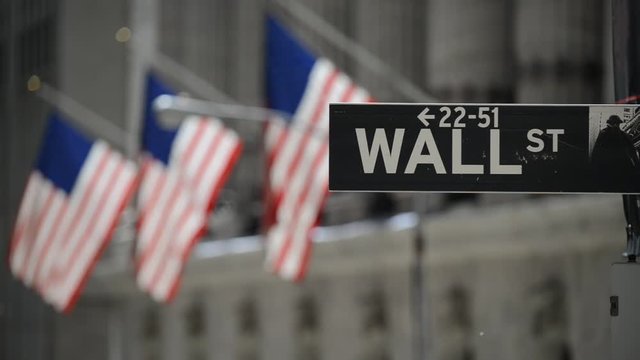 Wall Street sign with flags purposely blurred in background, lower Manhattan, downtown New York City, HD video