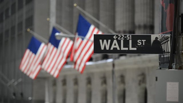 Wall Street sign with flags purposely blurred in background, lower Manhattan, downtown New York City, HD video
