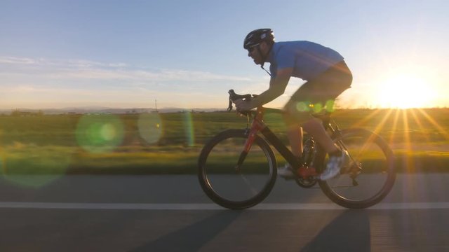 healthy man riding bycicle working out fitness outdoor at the sunset  tracking shot 4k from camera car
