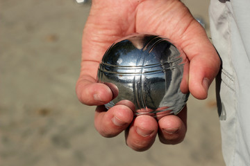 Petanque ball in hand of man. Close up.