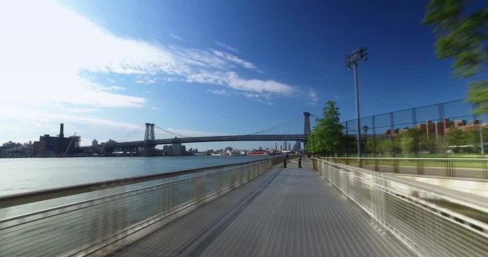 A bike rider's forward time lapse perspective on the East River Bikeway with the Williamsburg Bridge in the background.  	