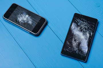 Two broken mobile phones on painted wooden table