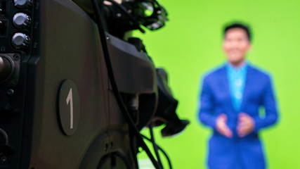 close-up a television camera with presenter out of focus in background