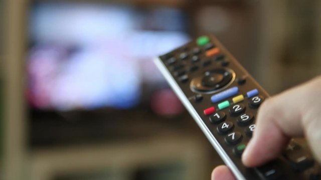 Guy switching through the TV program with a remote control