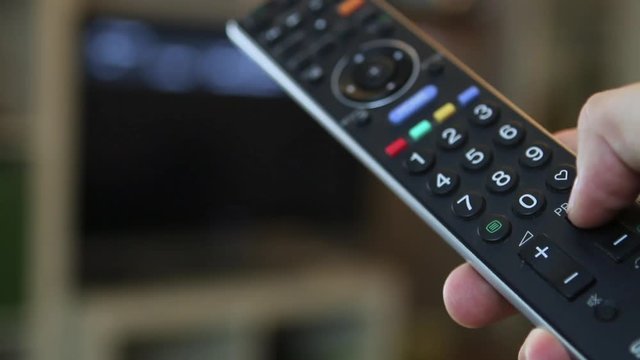 Guy switching through the TV program with a remote control