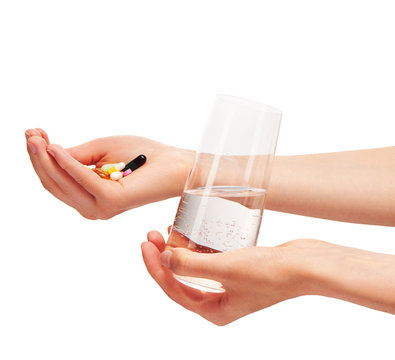 Hands holding glass with water and tablets and capsules