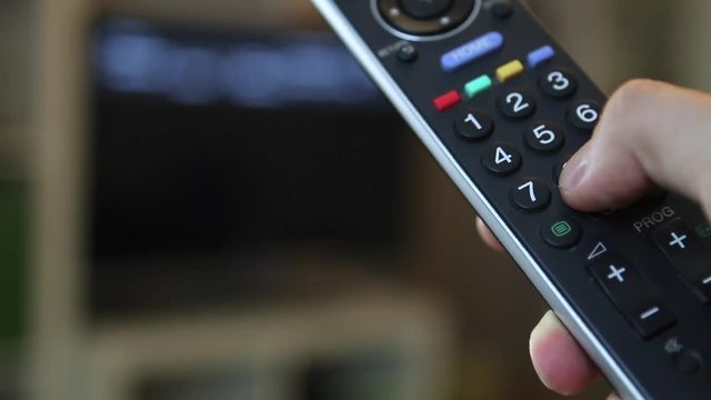 Guy switching through the TV program with a remote control