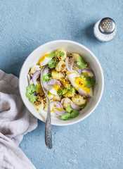 Potatoes and boiled egg salad with olive oil and mustard dressing. On a blue background, top view