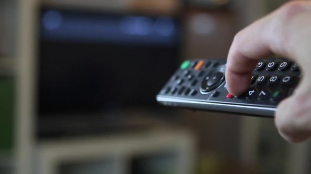 Guy switching through the TV program with a remote control