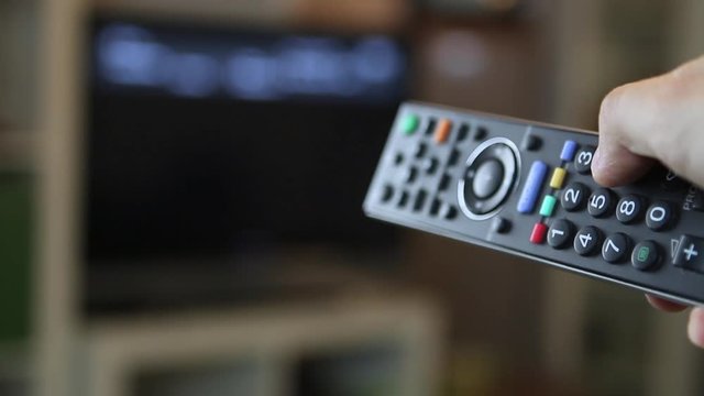 Guy switching through the TV program with a remote control
