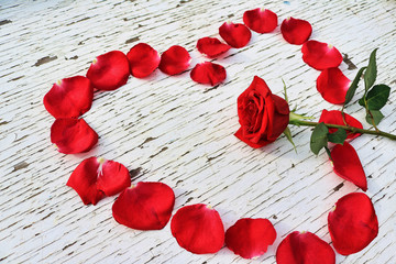 Red rose petals in the shape of a heart surrounding a red rose