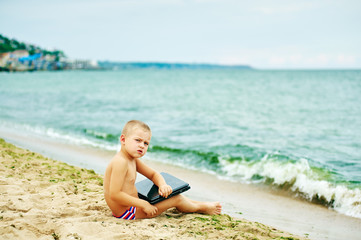 Fototapeta na wymiar boy sitting with a laptop on the beach